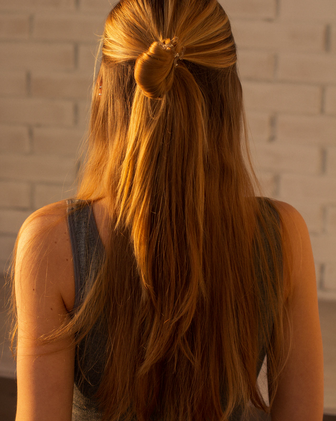 つやのあるロングヘアをゆるく結んだハーフアップの後ろ姿
